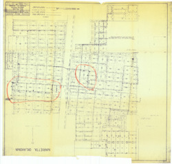 ["The map showcases the watermain system of Marietta, Oklahoma, highlighting the existing infrastructure. It includes the 1962 revisions, which propose new fire hydrants, valves, and mains, all marked in red. This watermain map is a diazotype, blueline print, measuring 33 3/4 by 35 5/16 inches, and is one of three annotated copies."]