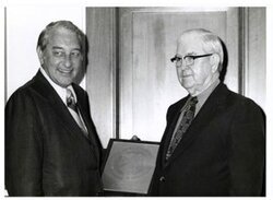 ["Black and white photograph of Tom Steed with Rex Davis, director of the Bureau of Alcohol, Tobacco and Firearms standing with an award."]