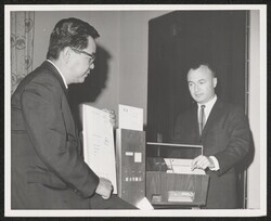 ["Caption: Dr. A. Leonard Diamond, right, demonstrates his teaching machine to Dr. Ralph M. Miwa, legislative assistant to Senator Daniel K. Inouye. A simple form of the teaching machine is in the center of the picture."]