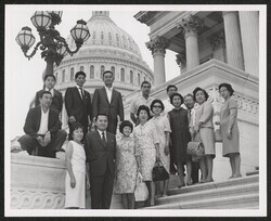 ["Caption: Club 100 members and their wives from the island of Hawaiʻi pictured on the Capitol steps with Senator Inouye while on a brief visit to Washington after a European tour. The veterans revisited some of the old Italian battlegrounds on which they f"]