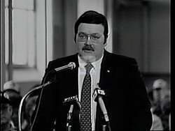 ["In a 1994 political ad, Democratic presidential candidate Duke Tremble presents himself as a confident and determined leader. Scenes show him addressing supportive crowds at various rallies, exuding leadership while speaking confidently at podiums, surrounded by American flags and campaign banners. The campaign emphasizes his readiness to lead with a hopeful and dedicated demeanor."]