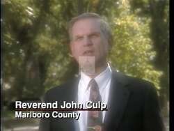 ["In the 1996 campaign ad, Democratic candidate John Spratt focuses on his dedication to reducing TV violence, passionately advocating for the V-CHIP legislation. He's seen in various settings, from Congress to a family living room, expressing his commitment to safeguarding family values and emphasizing the need for effective TV content control."]