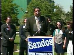 ["In the 1996 political TV ad, Democratic candidate Tim Sandos is prominently featured rallying support for his congressional campaign. Various scenes showcase him confidently speaking at podiums, receiving endorsements, and interacting with enthusiastic crowds waving campaign banners. Sandos is depicted as a passionate and dedicated family man, poised to serve in Congress."]