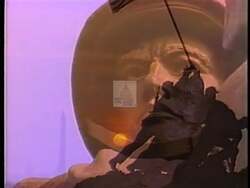 ["In a 1996 campaign ad, Democratic candidate Paul M. Barby passionately argues for defense spending reforms at various podiums, draped with American flags and campaign banners. He advocates reallocating funds from overseas military engagements to domestic priorities, emphasizing the need for a shift in U.S. defense spending and foreign policy."]