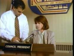 ["In her 1996 campaign ad, Democratic candidate Lydia C. Spottswood stands confidently at various podiums, advocating for fiscal responsibility and environmental protection. Her speeches emphasize \"Commitment to Change\" and \"Restoring Responsibility.\" The focus on responsible governance and addressing community concerns resonates with an attentive and enthusiastic audience, underscored by banners like \"Responsibility & Values.\""]