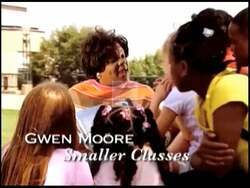 ["In her 2004 campaign ad, Democratic Party candidate Gwen Moore comes across as confident and determined, repeatedly speaking both directly to the camera and at a podium, conveying her leadership skills. Scenes include interactions with supporters and solo moments in a professional setting, highlighting her advocacy for education and healthcare reforms, as well as showcasing campaign slogans and posters. Moore's consistent message emphasizes change and leadership rooted in community values."]