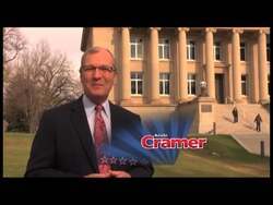 ["In Kevin Cramer's 2012 political ad, he confidently addresses the camera in various settings, pledging strong leadership, fiscal responsibility, and economic growth. Throughout scenes set at podiums and in professional environments, Cramer emphasizes his dedication to constituent needs and national issues, promising commitment and assertive congressional advocacy against the backdrop of American flags and campaign banners."]