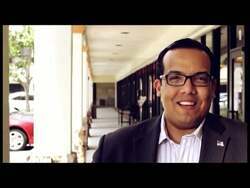 ["In his 2012 campaign ad, Republican candidate Juan Eliel Garcia appears determined and confident, frequently filmed against an American flag backdrop, embodying leadership and promoting change. He addresses the nation from various settings including a podium and an office, earnestly advocating for his presidential bid to an attentive crowd."]